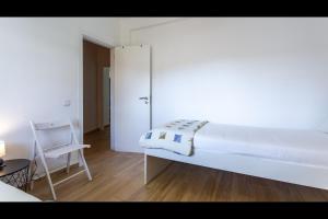 a white bedroom with a bed and a chair at Falésia Modern Flat W/Balcony & Pool by LovelyStay in Albufeira