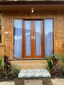 una porta d'ingresso di una casa in legno con finestre di D'Yoga Bamboo Cabin a Kintamani