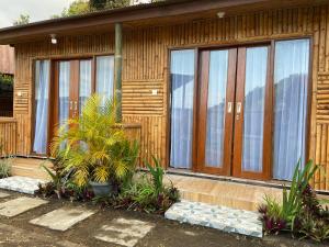a house with wooden doors and plants in front of it at D'Yoga Bamboo Cabin in Kintamani