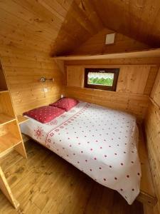 a bed in a wooden cabin with a window at Tiny-house in Wihr-au-Val