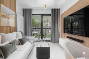 uma sala de estar com um sofá branco e uma televisão em Shellter Apartments 117 J - by Jantar Apartamenty em Rogowo