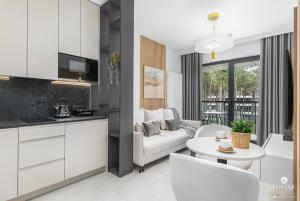 uma cozinha e sala de estar com um sofá e uma mesa em Shellter Apartments 117 J - by Jantar Apartamenty em Rogowo