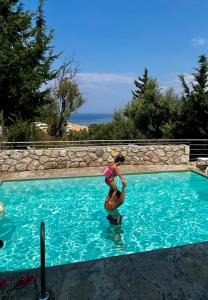 Uma jovem está a saltar para uma piscina. em Katerina's Village Agios Nikitas em Áyios Nikítas