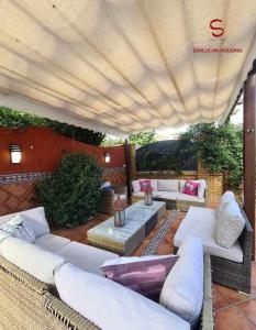 an outdoor patio with white couches and a large umbrella at Casa Hermosilla céntrica con piscina y jardín in Sanlúcar de Barrameda