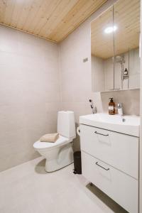 a white bathroom with a toilet and a sink at Studio Haarajoki in Järvenpää