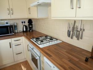 uma cozinha com armários brancos e um forno com placa de fogão em Seair em Rustington
