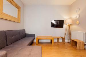 uma sala de estar com um sofá, uma mesa e uma televisão em Bright & Homely City Centre Apartment near Holyrood em Edimburgo