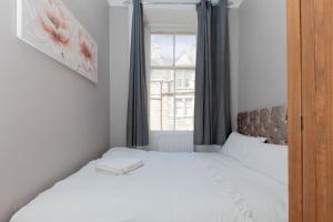 a bedroom with a white bed with a window at Bright & Homely City Centre Apartment near Holyrood in Edinburgh