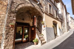 une entrée à un bâtiment avec des plantes en pot devant lui dans l'établissement Ca'Spadolino, à Spello