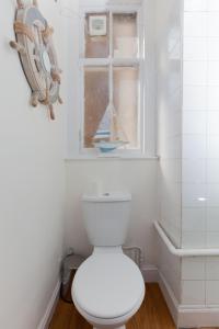 a white bathroom with a toilet and a window at Bright & Homely City Centre Apartment near Holyrood in Edinburgh