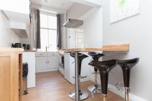 a kitchen with a counter and stools in a room at Bright & Homely City Centre Apartment near Holyrood in Edinburgh