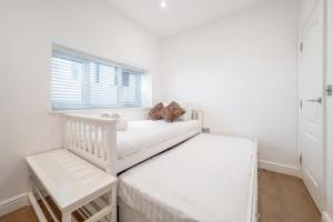 a white bedroom with two beds and a window at Maida Vale Gem by Little Venice with Stunning Garden in London