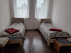 two beds in a room with two windows at Gästewohnung Alt Salbke mit Küche in Magdeburg