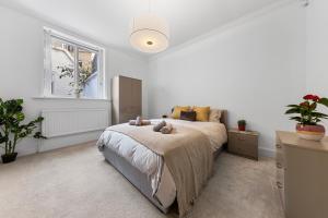 a white bedroom with a bed and a window at Harrods 2 Bed Lux Flat w/patio in London