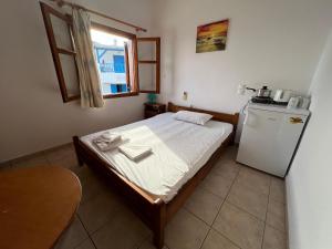 a small bedroom with a bed and a refrigerator at Panorama Zimmer und Apartments Lentas in Lentas