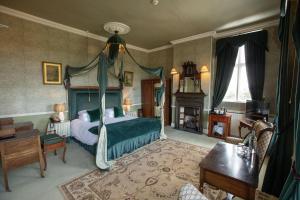 a bedroom with a canopy bed and a fireplace at Grafton Manor Hotel in Bromsgrove