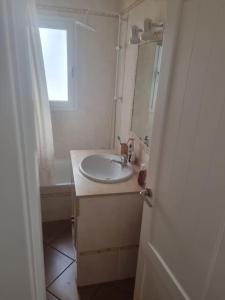 a white bathroom with a sink and a window at Apartamento Cerca de la Playa in Almería