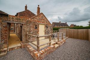 a brick building with a yellow door and a fence at The Barrel Room at The Northbrook Arms in Winchester