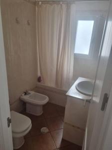 a white bathroom with a toilet and a sink at Apartamento Cerca de la Playa in Almería +17 photos