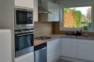 una cocina con electrodomésticos de acero inoxidable y una ventana en Un cocon entre ville et nature, en Annappes