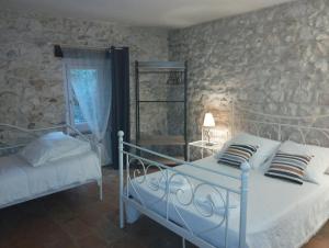 a bedroom with two beds and a stone wall at Logis Hotel Restaurant L'Esquielle in Saint-Géniès-de-Malgoirès +29 photos