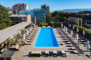 a swimming pool on the roof of a building with lounge chairs at Holiday Inn - Tbilisi, an IHG Hotel in Tbilisi City