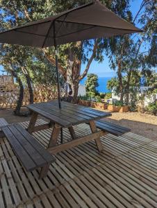 a wooden picnic table with an umbrella on a deck at Piana in Lumio