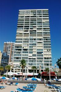 ein großes Gebäude mit Liegestühlen davor in der Unterkunft Apartamentos Santa Margarita - Arca Rent in Benidorm