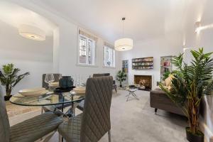 a dining room with a table and chairs and a fireplace at Harrods 2 Bed Lux Flat w/patio in London