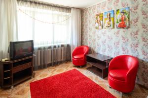 Киев في بتروبافلوفسك: غرفة معيشة فيها كرسيين احمر وتلفزيون