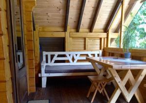 un porche de una cabaña de madera con un banco y una mesa en Еко будинок в горах, en Verkhniy Bystryy