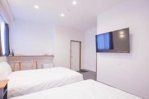 um quarto de hotel com duas camas e uma televisão de ecrã plano em Cozy 4-Guest Stay in Heart of Asakusabashi, Tokyo DSoY em Tóquio