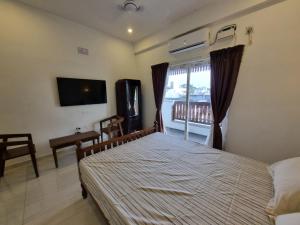 um quarto com uma cama, uma televisão e uma janela em RVS Chalet em Pondicherry