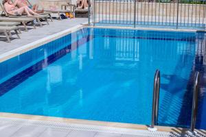 a large blue swimming pool with people sitting on chairs at Peramis Hotel & Spa in Antalya