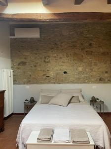 una camera da letto con un grande letto bianco e un muro in pietra di Alloggio con camino nel borgo del castello ad Albinea