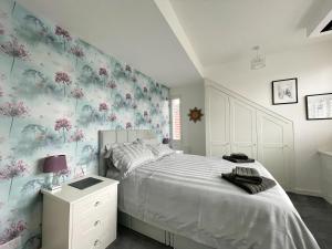 um quarto com uma cama branca com flores na parede em Lovely Comfortable 3BR Property em Nether Edge