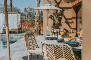 una mesa con 2 sillas y copas de vino y una sombrilla en Villa 3 chambres Piscine - Golf, en Marrakech