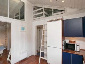 a loft bed in a kitchen with a microwave and a refrigerator at 11 person holiday home in Str by in Strøby