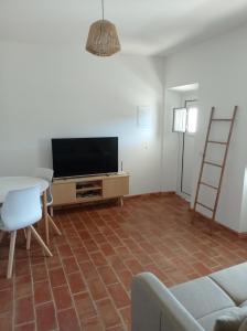 ein Wohnzimmer mit einem TV und einem Tisch in der Unterkunft Casa do Livramento in Luz de Tavira