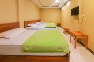 2 camas con sábanas verdes en una habitación en Delvia Bromo Homestay Mitra RedDoorz, en Pasuruan