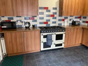 a kitchen with a stove and wooden cabinets at Berks Luxury serviced Apartments,5 Bedrooms, 5 double beds, 2 bathrooms, free super fast WiFi & parking in Earley