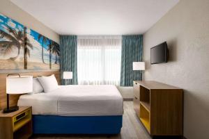 a hotel room with a bed and a television at Days Inn by Wyndham Miami Airport North in Miami