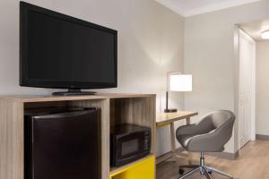 a room with a television and a chair and a desk at Days Inn by Wyndham Miami Airport North in Miami