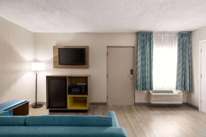 a living room with a blue couch and a television at Days Inn by Wyndham Miami Airport North in Miami