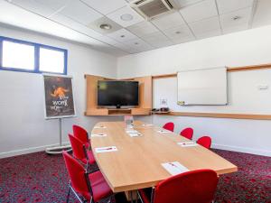 una sala de conferencias con una gran mesa de madera y sillas rojas en ibis Marseille Centre Gare Saint Charles, en Marsella