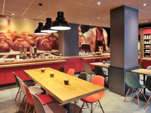 un restaurant avec des tables et des chaises et une grande fresque murale. dans l'établissement ibis Lyon Centre, à Lyon