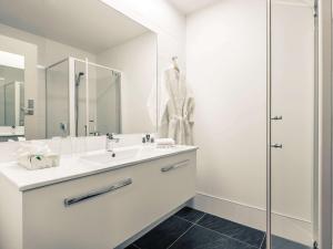 a white bathroom with a sink and a shower at Mercure Queenstown Resort in Queenstown