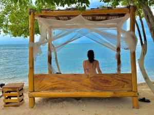 a woman sitting on a bed on the beach at El Cocotal Tintipán By Ashram in Tintipan Island