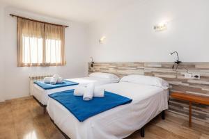 two beds in a room with white and blue sheets at Sa Coromina in Cala Ratjada