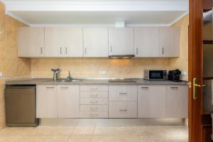 a kitchen with white cabinets and a sink and a microwave at Sa Coromina in Cala Ratjada